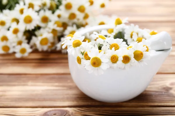 Kamomillblommor i mortel på brunt träbord — Stockfoto