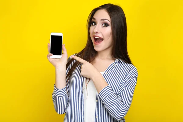 Hermosa mujer joven con teléfono inteligente sobre fondo amarillo —  Fotos de Stock