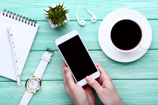 Smartphone en manos femeninas con taza de café, notebook y wris — Foto de Stock
