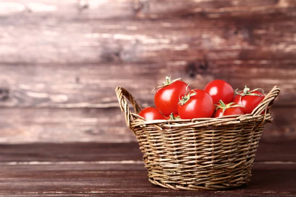 Tomat segar dan matang dalam keranjang di atas meja kayu — Stok Foto