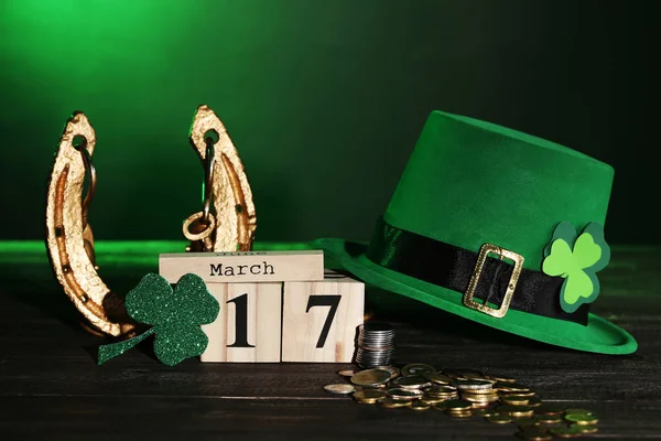 Hojas de trébol con calendario de madera, sombrero verde, herradura y moneda — Foto de Stock