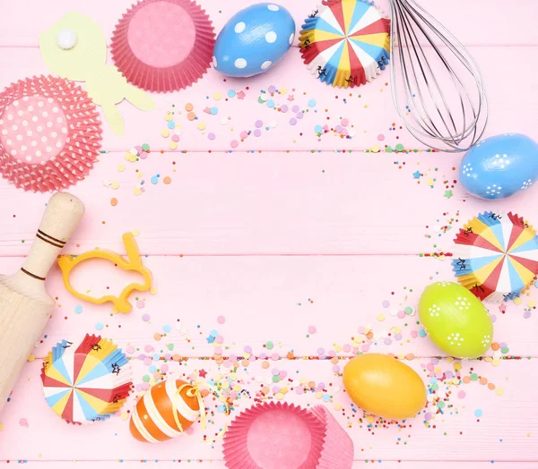 Œufs de Pâques avec confettis et ustensiles de kithcen sur ta en bois rose — Photo