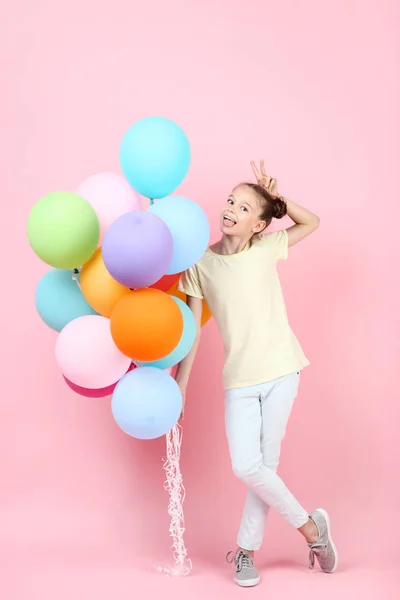 Menina bonito com balões coloridos no fundo rosa — Fotografia de Stock