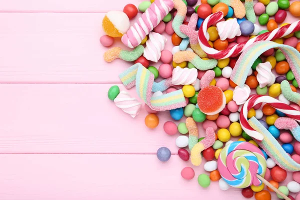 Doces doces e pirulitos na mesa de madeira rosa — Fotografia de Stock