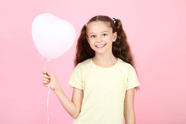 Cute young girl with balloon on pink background