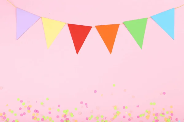 Colorful confetti and paper flags on pink background — Stock Photo, Image