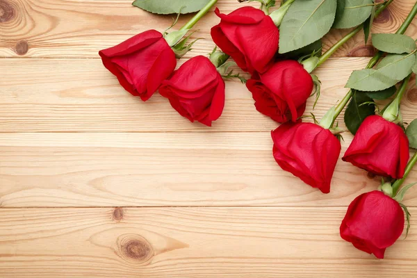 Ramo de rosas rojas sobre mesa de madera marrón — Foto de Stock