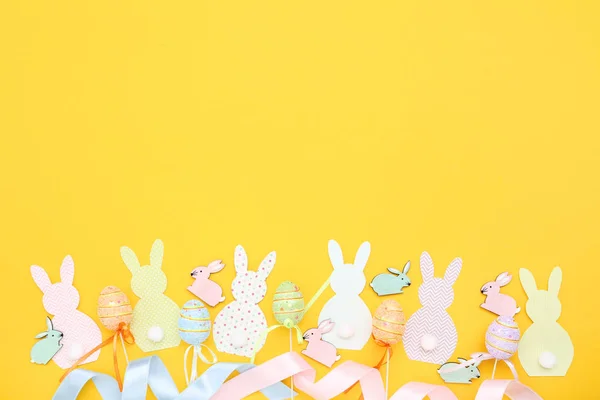 Coelhos de Páscoa e ovos no fundo amarelo — Fotografia de Stock