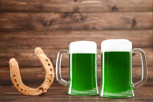 Saint Patrick. Bière verte dans des tasses avec fer à cheval doré sur w — Photo