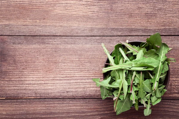 Löwenzahnblätter in Schale auf Holztisch — Stockfoto