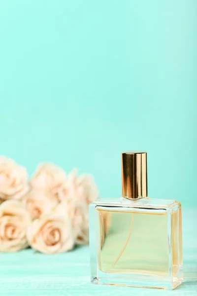 Frasco de perfume con rosas sobre fondo de menta — Foto de Stock