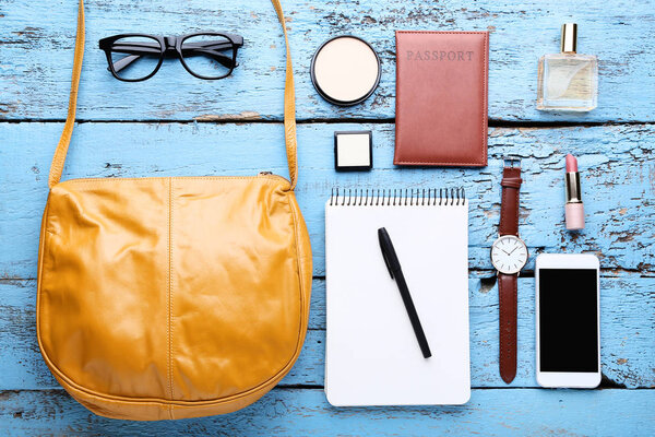 Handbag with cosmetics, smartphone, notebook and wrist watch on 
