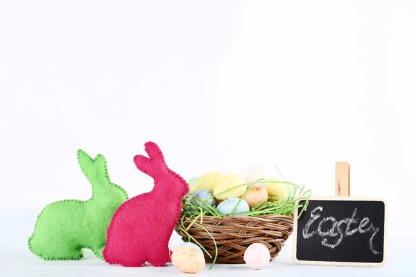 Ovos coloridos com coelhos de tecido e palavra Páscoa em backg branco — Fotografia de Stock
