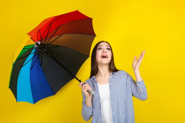 Young girl with colorful umbrella on yellow background — Stock Photo, Image