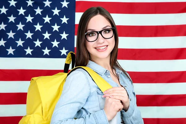 Joven estudiante con mochila sobre fondo de bandera americana — Foto de Stock