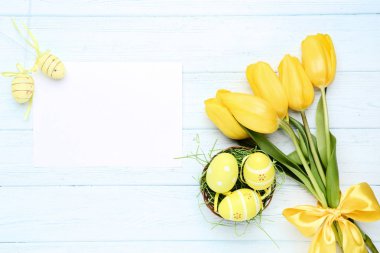 Paskalya yumurtaları ile sarı lale ve woode üzerinde boş kağıt levha