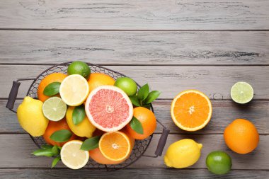 Ahşap masada sepette yeşil yapraklarla narenciye meyveleri