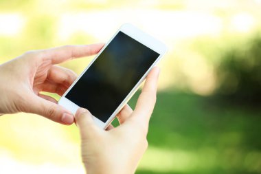 Holding ve smartphone üzerinde arka plan bulanık kullanarak kadın