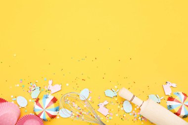 Sarı artalan üzerinde mutfak malzemesi ile Paskalya tavşanları ve yumurta