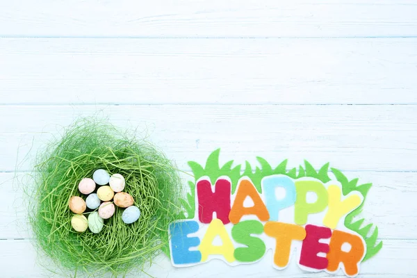 Texto Feliz Pascua con huevos de colores en la mesa de madera — Foto de Stock