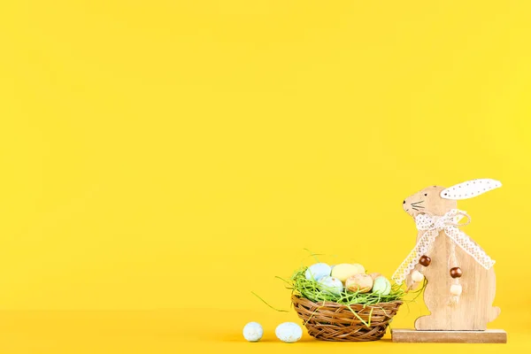 Pisanki z drewnianymi królików na żółtym tle — Zdjęcie stockowe