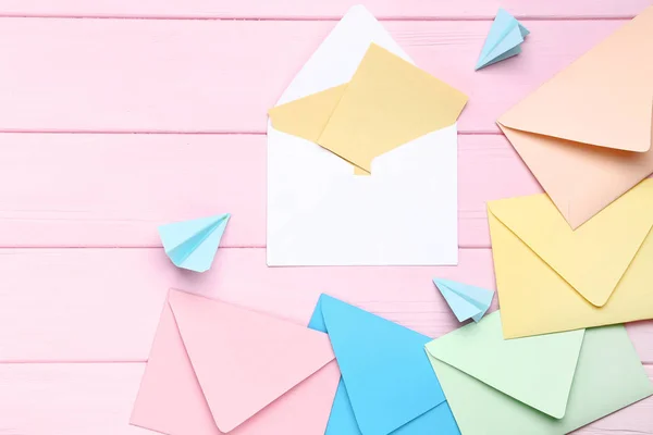 Enveloppes colorées avec des plans en papier sur table en bois rose — Photo