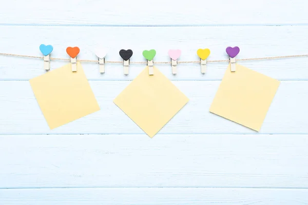 Clothespins kolorowe serca i pustych kartek papieru hangi — Zdjęcie stockowe