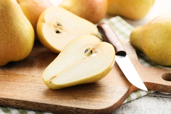 Ripe pears with cutting board and knife on wooden table — Stock Photo, Image