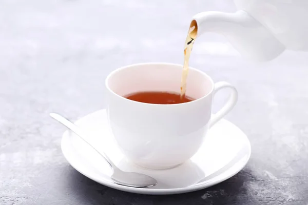 Verter el té de la tetera en una taza blanca sobre una mesa de madera —  Fotos de Stock