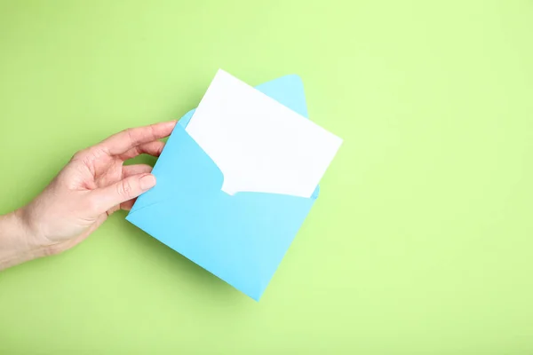 Female hand with paper envelope on green background — Stock Photo, Image