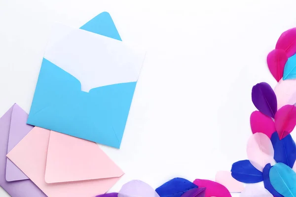 Sobres de papel con plumas de colores sobre fondo blanco —  Fotos de Stock