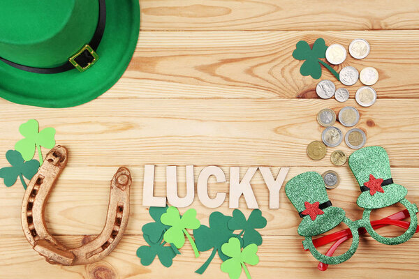 Золотая подкова с листьями клевера, монетами, зеленой шляпой и стаканами
