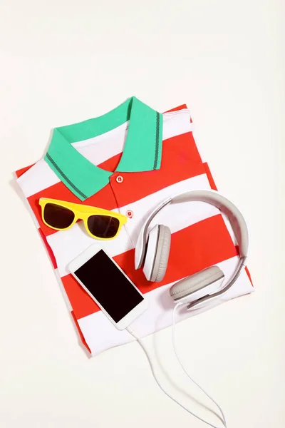 Smartphone met koptelefoon, zonnebrillen en gestreept t-shirt op be — Stockfoto