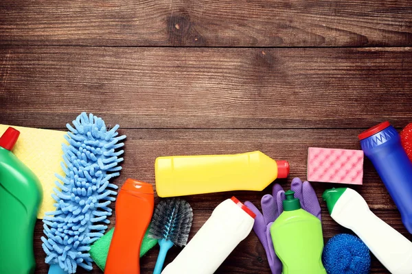 Botellas con detergente y herramientas de limpieza sobre mesa de madera —  Fotos de Stock