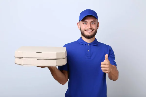 Człowiek dostawy pizzy w kartony na szarym tle — Zdjęcie stockowe