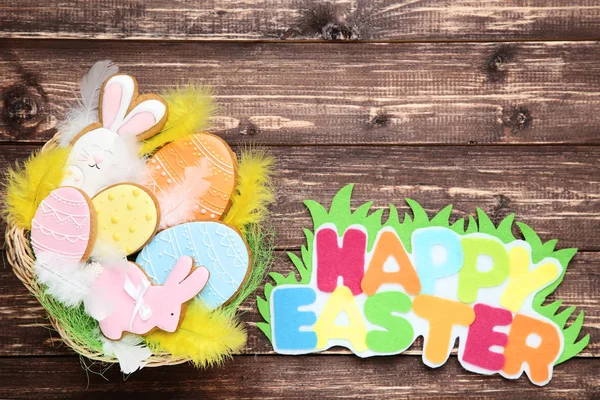 Galletas de jengibre en cesta con texto Feliz Pascua en madera t — Foto de Stock