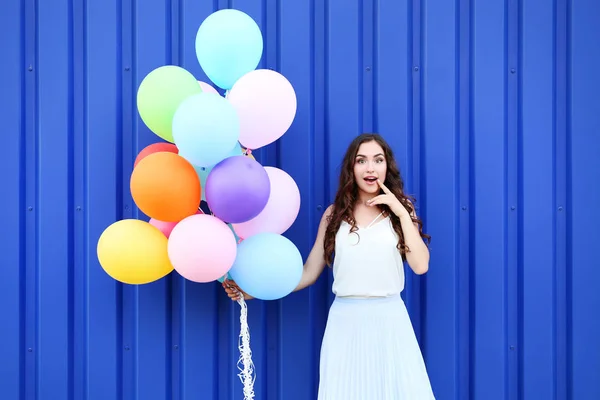 Ragazza carina con palloncini colorati su sfondo blu — Foto Stock