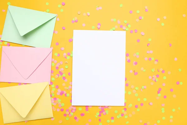 Enveloppes colorées avec papier blanc et confettis sur fond jaune — Photo