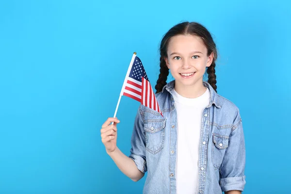 Jong meisje die houdt van een Amerikaanse vlag op blauwe achtergrond — Stockfoto