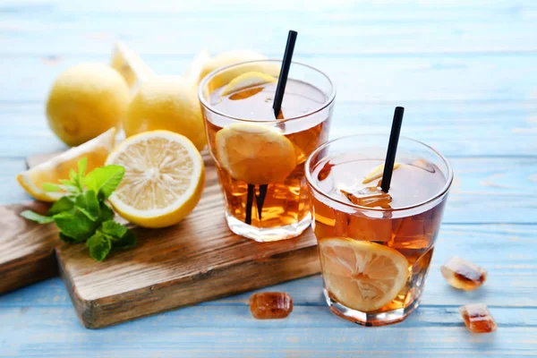Ijs thee in glazen met citroen en munt bladeren op houten tafel — Stockfoto