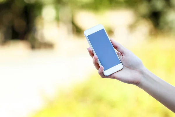 Woman holding and using smartphone on blurred background Stock Picture
