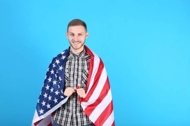 Genç adam bir Amerikan bayrağı mavi arka plan üzerinde tutan