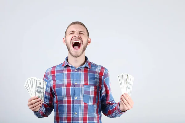 Joven feliz con billetes de dólar sobre fondo gris — Foto de Stock