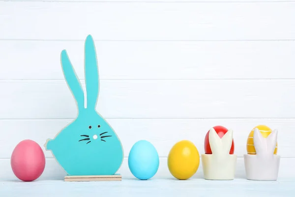 Ovos de páscoa coloridos com coelho de madeira azul sobre fundo branco — Fotografia de Stock