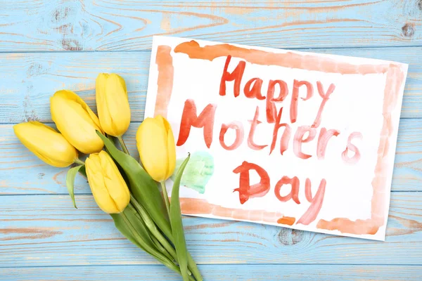 Tarjeta de felicitación para el Día de las Madres con tulipanes amarillos en madera azul —  Fotos de Stock