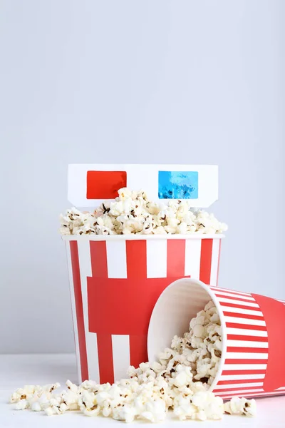 Popcorn in striped buckets with glasses on grey background — Stock Photo, Image