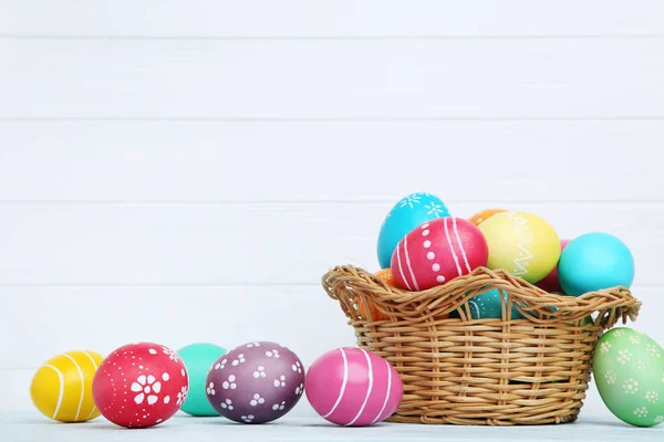 Colorate uova di Pasqua in cesto su sfondo di legno — Foto Stock