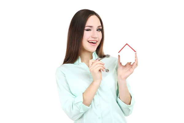 Mujer joven mostrando llaves y casa de madera sobre fondo blanco —  Fotos de Stock