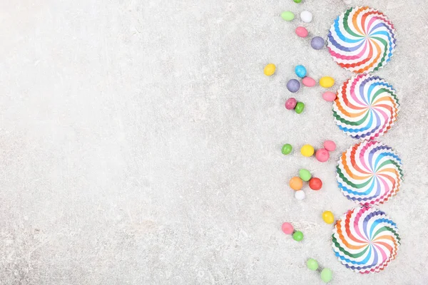 Coloridas fundas para cupcakes con caramelos sobre fondo gris — Foto de Stock