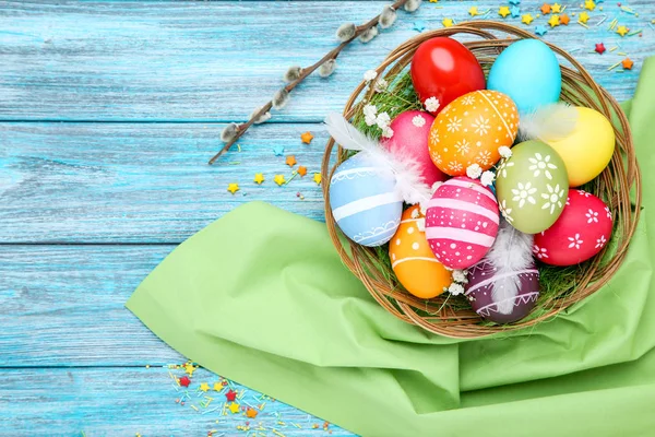 Oeufs de Pâques colorés dans le panier avec des fleurs de gypsophile sur bleu w — Photo